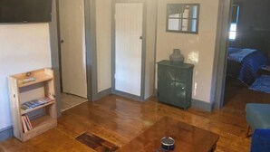 A room with a wooden floor, a small table with a cup, a bookshelf, a door, a mirror, and a bed with a blue blanket. - #4 Quaint 1 bedroom apartment in Historic Building (Newburgh)