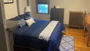 A bedroom with a bed, a dresser, a window, and an air conditioning unit. - #4 Quaint 1 bedroom apartment in Historic Building (Newburgh)