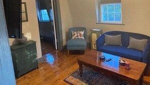 A living room with a blue sofa, a wooden coffee table, and a patterned rug. - #4 Quaint 1 bedroom apartment in Historic Building (Newburgh)