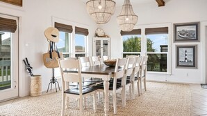 A dining area with a wooden table, white chairs, and a chandelier.