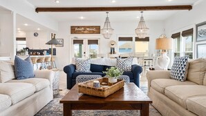 A spacious living room with two sofas, a coffee table, and a kitchen in the background.