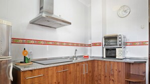 Eine Küche mit Holzschränken, einem Edelstahl-Spülbecken, einem Doppelbackofen und einer dekorativen Spritzschutzwand.