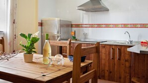 Eine Küche mit Holzausstattung, einer Edelstahl-Dunstabzugshaube, einem Blumentopf, einer Weinflasche und einem Weinglas auf einem Holztisch.
