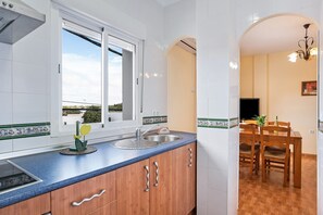 A kitchen with a window, sink, and wooden cabinets.