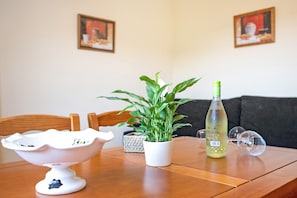 A dining table with a white ceramic bowl, a potted plant, a bottle, and a pair of glasses.
