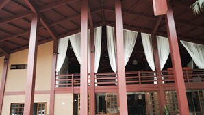 A building with a red wooden structure, multiple windows with white curtains, and a balcony with a railing. - Delta Maresias Club by SmartSharing (São Sebastião)