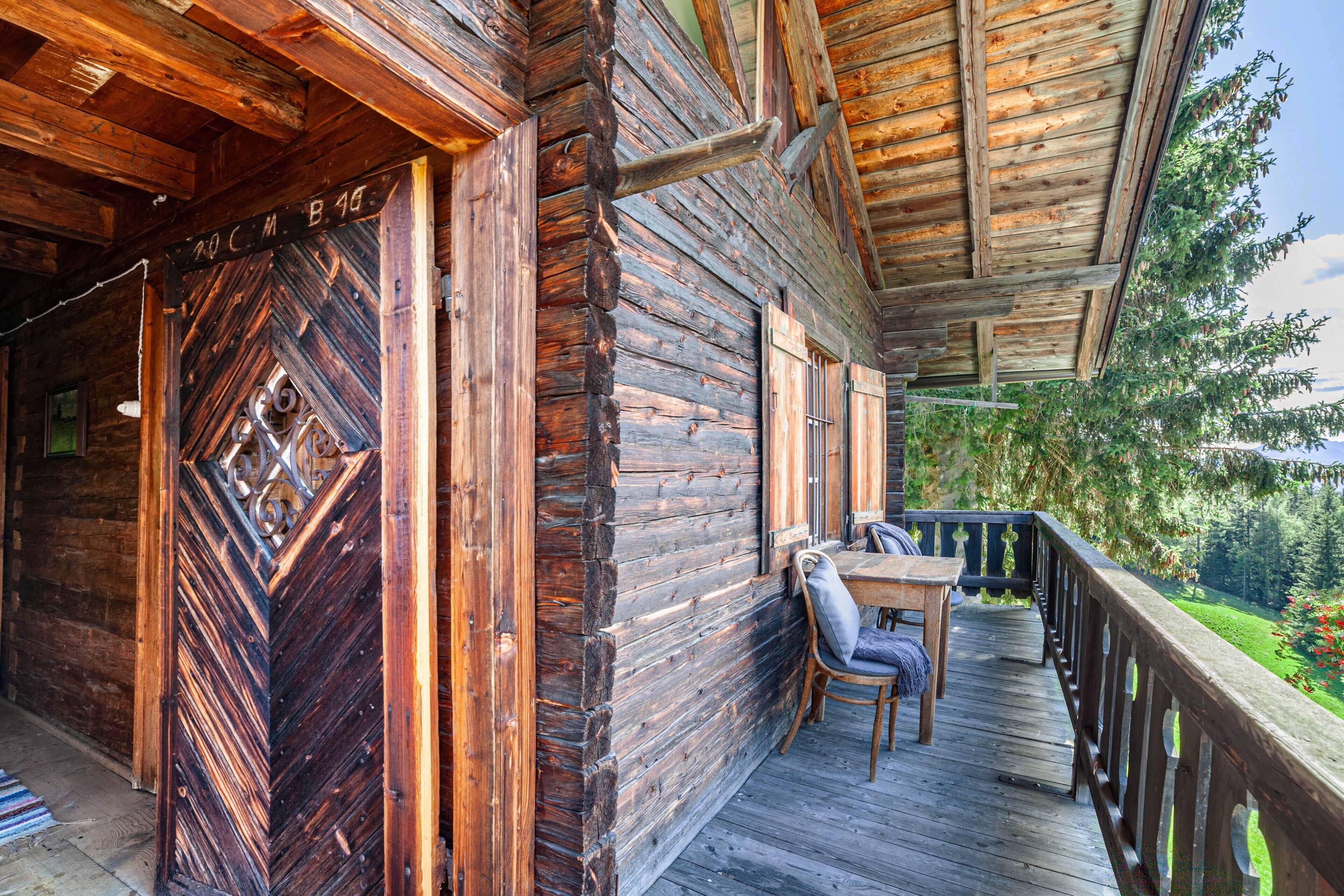 Eine Holzhütte mit einem Balkon, einem Tisch und Stühlen.