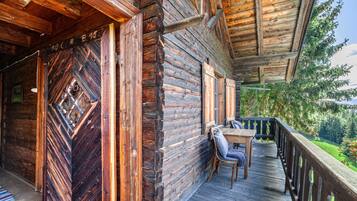 Eine Holzhütte mit einem Balkon, einem Tisch und Stühlen.