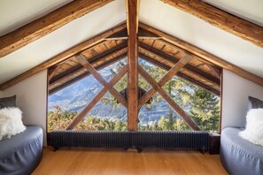 A room with a sloped ceiling, wooden beams, a large window with a mountain view, and a radiator. - Chalet 'Bergchalet Ifinger' Mountain View, Garden & Wi-Fi (Scena)