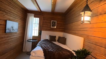 Ein Zimmer mit Holzwänden, einem Bett, einem kleinen Tisch und einem Blumentopf.