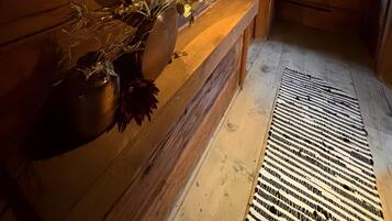 A wooden interior with a round mirror, a wooden bench, and a small window.