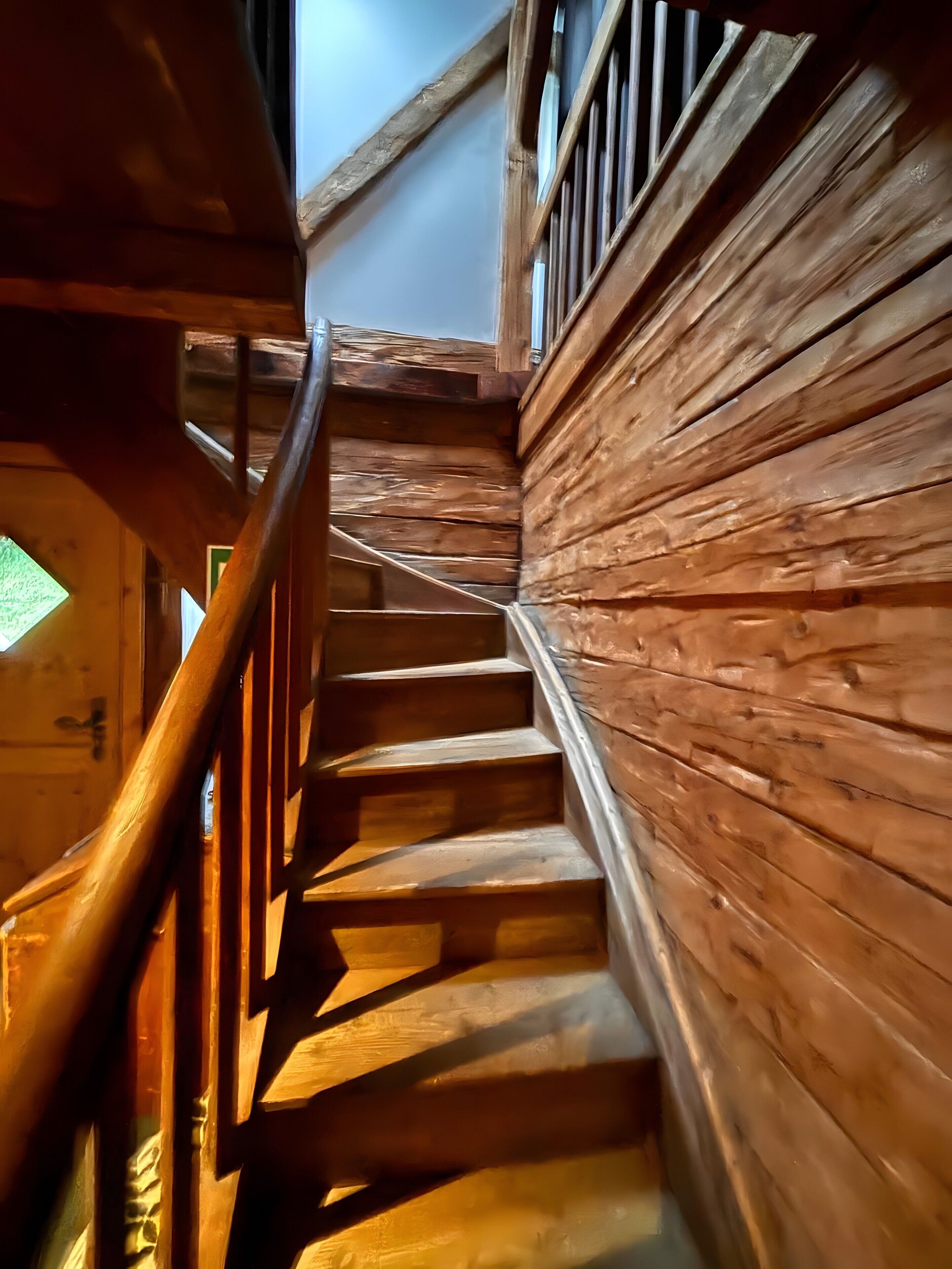 Eine Holztreppe mit Handlauf, die zu einer oberen Ebene führt.