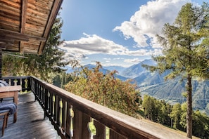 A wooden deck with a railing overlooking a mountainous landscape.