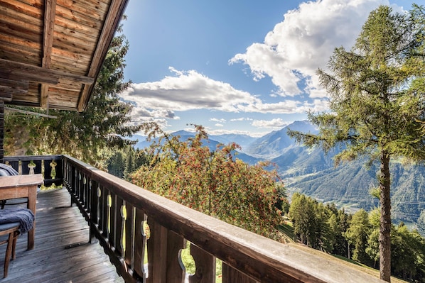 A wooden deck with a railing overlooking a mountainous landscape.