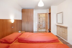 A bedroom with a bed, wooden wardrobe, and a mirror on the wall.