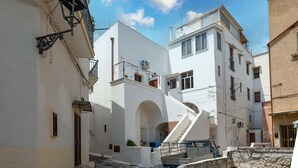 A narrow street with white buildings, a visible staircase, and a parked truck. - Holiday Home "Sg Standard" with Landmark View, Terrace & Wi-Fi (Massafra)