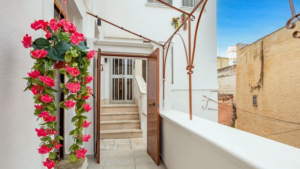 A narrow outdoor corridor with a staircase leading to a door, a hanging flower arrangement, and a white wall. - Holiday Home "Sg Standard" with Landmark View, Terrace & Wi-Fi (Massafra)