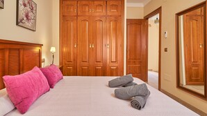 A hotel room with a large bed, wooden wardrobe, and a mirror. - Holiday Home Casa Murillo with Sea View, Terrace & Wi-Fi (Nerja)