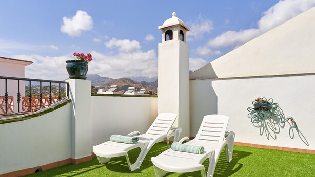 A rooftop terrace with two white lounge chairs, a potted plant, and a view of mountains. - Holiday Home Casa Murillo with Sea View, Terrace & Wi-Fi (Nerja)