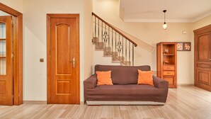 A living room with a brown sofa, wooden doors, a staircase, and a wooden cabinet. - Holiday Home Casa Murillo with Sea View, Terrace & Wi-Fi (Nerja)