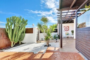 Un espace extérieur aménagé avec un cactus, un palmier et une clôture en bois.