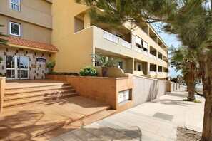 Ein mehrgeschossiges Gebäude mit einer gefliesten Eingangshalle, einem Balkon und einer Palme.