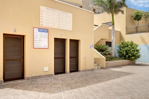 A building with three closed doors, a staircase, and a sign with text.