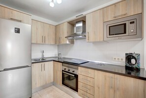 A modern kitchen with wooden cabinets, stainless steel appliances, and a microwave.