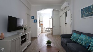 A living room with a flat-screen TV, a sofa with floral cushions, a coffee table, and a plant. - Italianway - Dogali 55 (Santa Margherita Ligure)