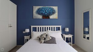 A bedroom with a bed, white headboard, two bedside tables with lamps, a wall-mounted painting, and a wardrobe. - Italianway - Dogali 55 (Santa Margherita Ligure)