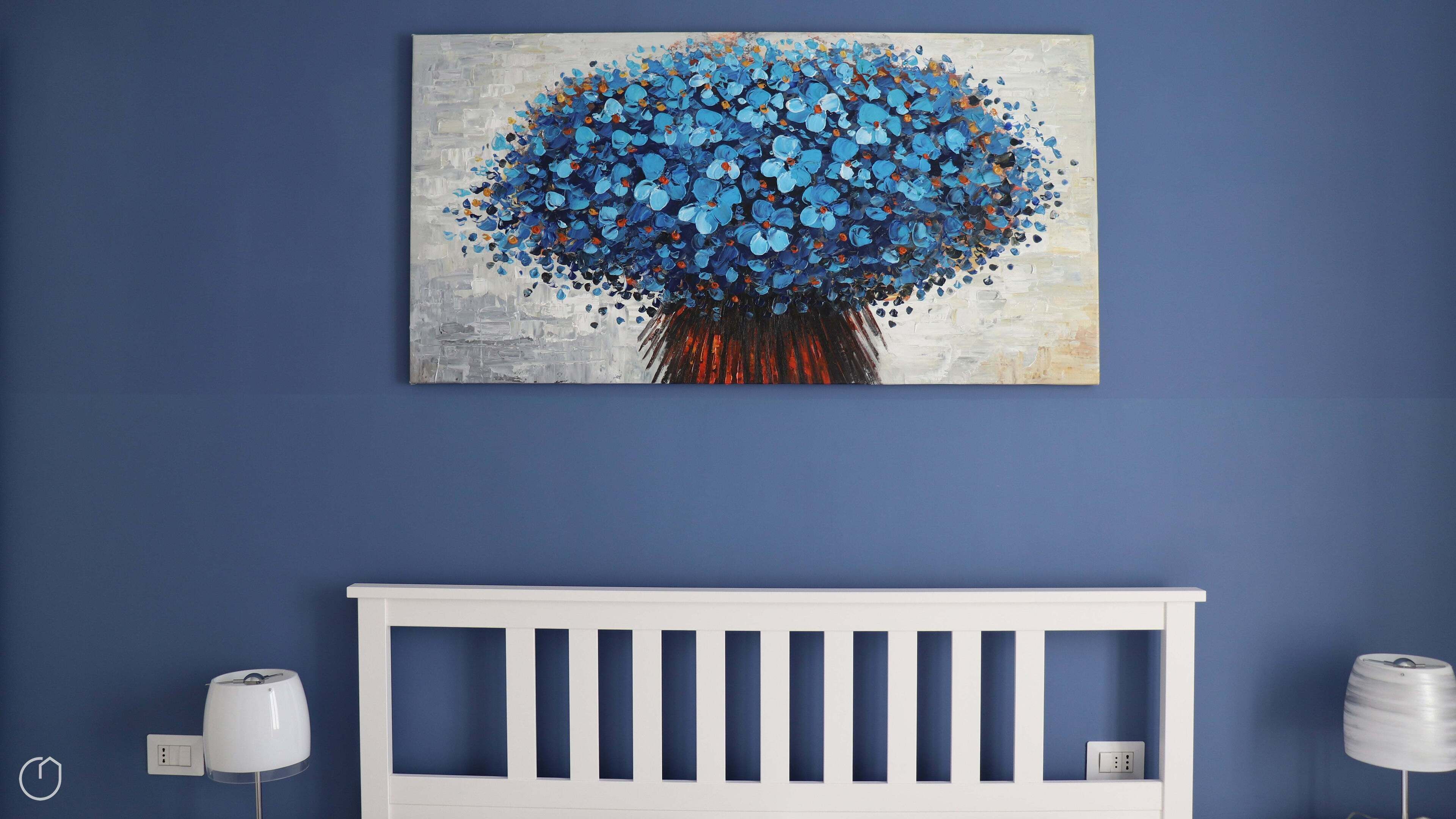 A room with a blue wall, a white crib, and a painting of a blue flower.