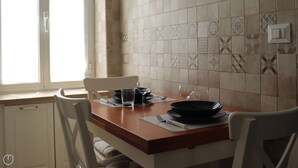 A dining area with a wooden table set for two, white chairs, and a tiled backsplash. - Italianway - Dogali 55 (Santa Margherita Ligure)