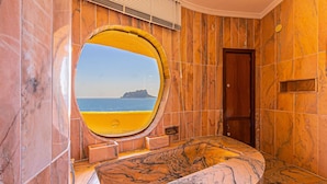 A bathroom with a large oval mirror, a marble sink, and a view of the sea. - Villa DIANA by Abahana Villas (Teulada)