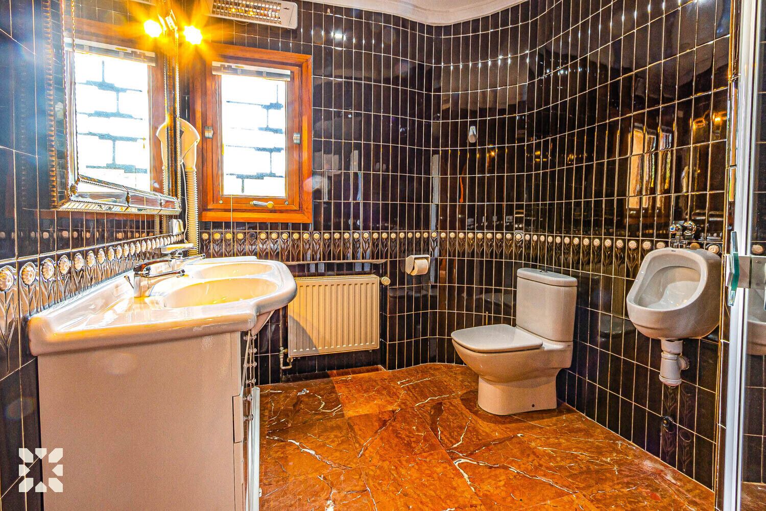 Un baño con piso de mármol, lavamanos, inodoro y orinal.