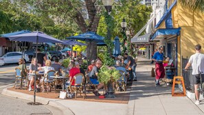 Outdoor seating with umbrellas, a street view, and a storefront with a sign. - Perfect Downtown Space-Walk to Library, Theater, REstaurants & Shops! (Sarasota)