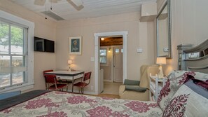 A bedroom with a bed, a desk with chairs, a mirror, and a door leading to another room. - Perfect Downtown Space-Walk to Library, Theater, REstaurants & Shops! (Sarasota)