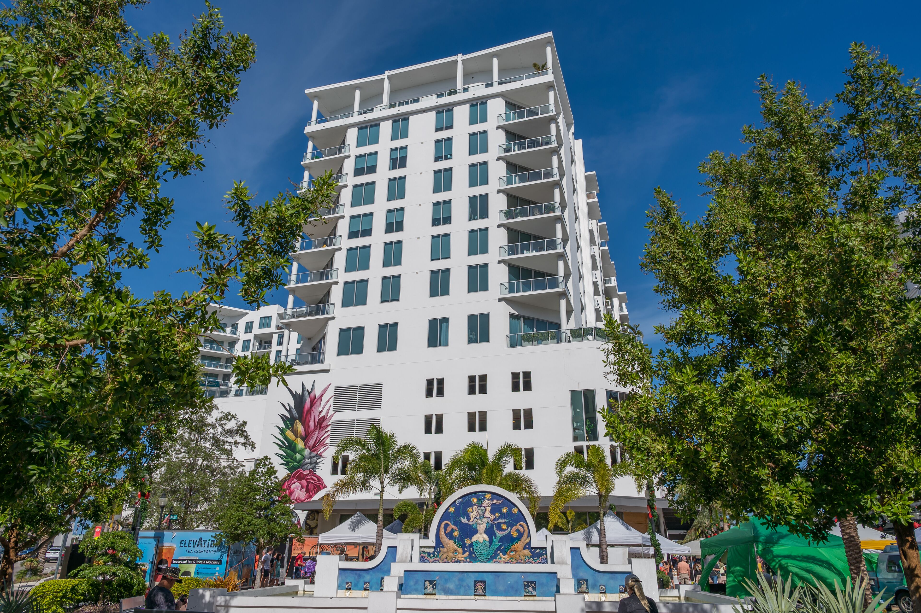 Ein mehrstöckiges Hotel mit weißer Fassade, Balkonen und einem dekorativen Eingang mit floralem Muster.