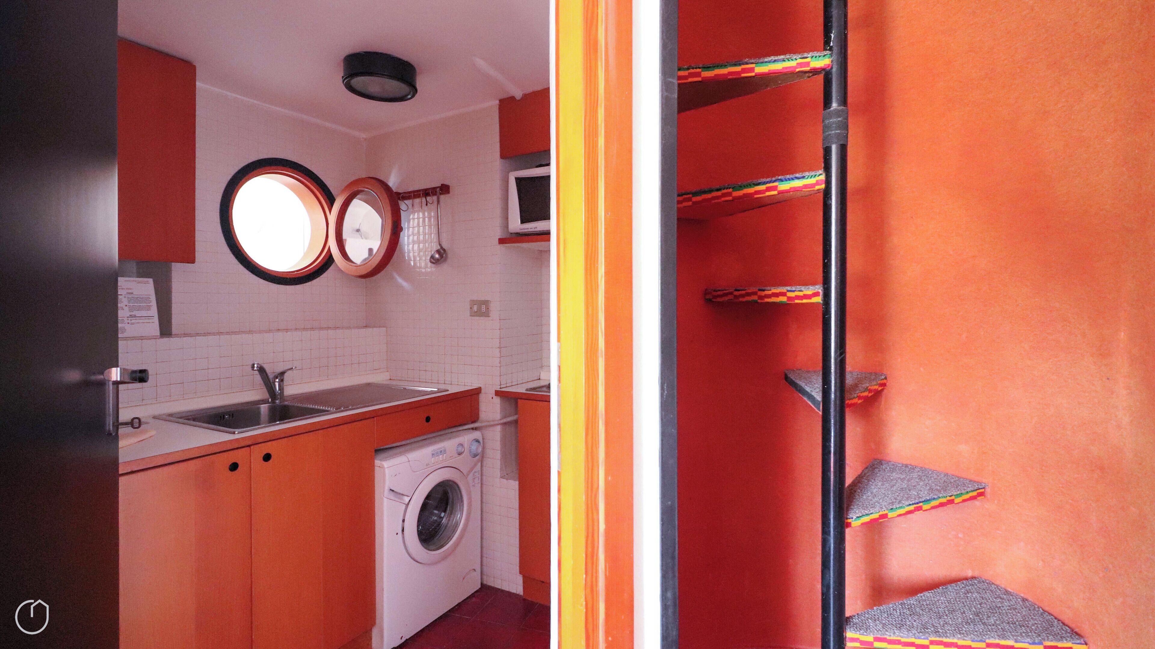 Una cocina compacta con lavadora, fregadero y microondas.
