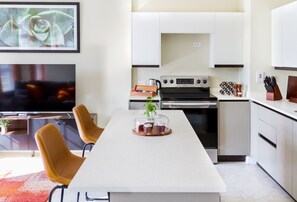 A modern kitchen with white cabinets, a central island, and a dining area with two chairs.