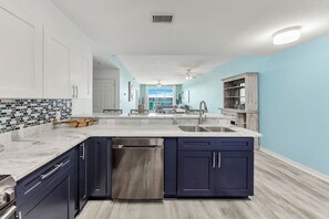 Una cocina moderna con armarios azul oscuro, una encimera blanca y un salpicadero con azulejos azules y grises.