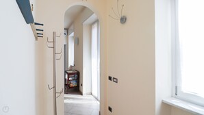 A hallway with a door on the left, a small table with boxes in the center, and a window on the right. - Italianway - Ruffini 20 (Santa Margherita Ligure)