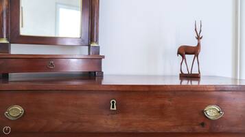 Une commode en bois, surmontée d’un miroir et d’une figurine de cerf.