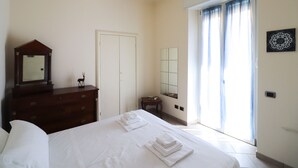 A hotel room with a bed, a dresser, a mirror, a small table, and a window with curtains. - Italianway - Ruffini 20 (Santa Margherita Ligure)
