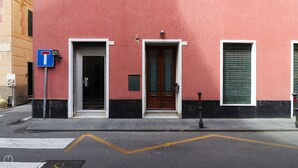 A building with a red facade, a blue parking sign, and a pedestrian crossing. - Italianway - Ruffini 20 (Santa Margherita Ligure)
