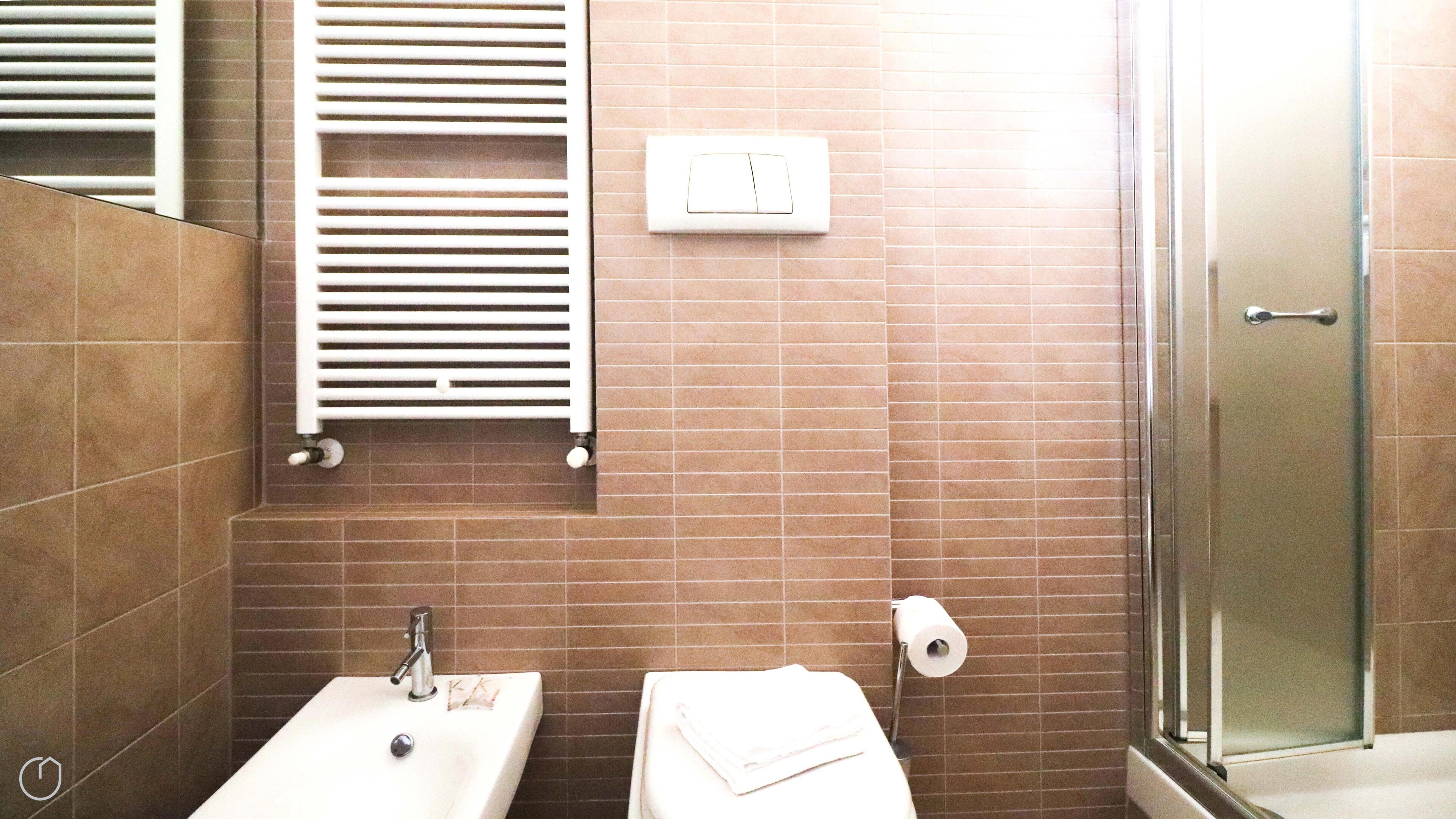 A bathroom with a sink, toilet, towel, and a glass shower enclosure.