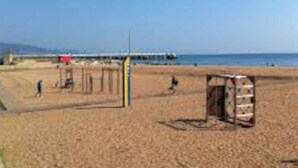 A sandy beach with a wooden structure, possibly a beach hut, and a pier in the background. - Tranquilo. Cerca de la Playa. Bien Comunicado (Sant Adrià de Besòs)