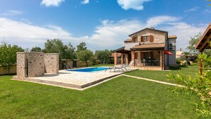 Une maison à deux étages avec une piscine, une terrasse et une pelouse bien entretenue.