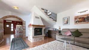 Un salon avec une cheminée, un canapé, une table basse et un escalier.