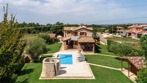 Une villa dotée d’une piscine, d’une terrasse en pierre et offrant une vue sur les environs.