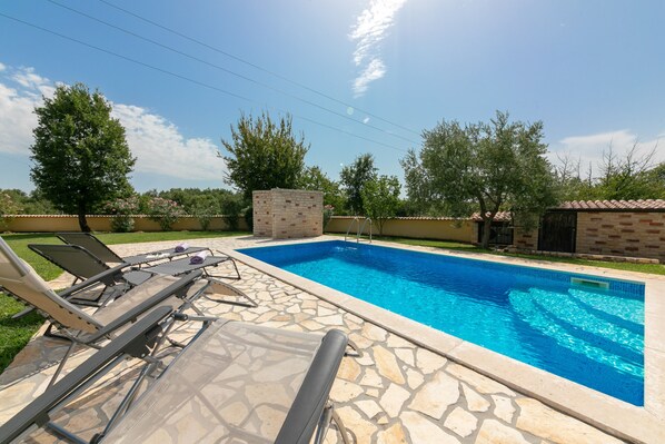 A swimming pool with lounge chairs and a stone deck.